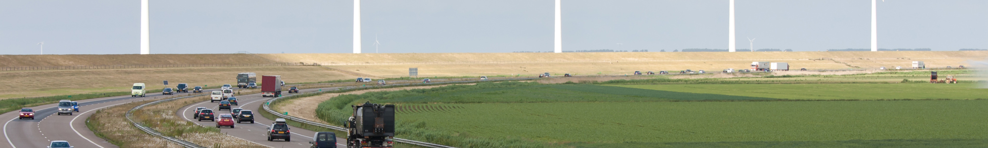 Motorway With A Line Of Big Windturbines Behind It Shutterstock 78165178